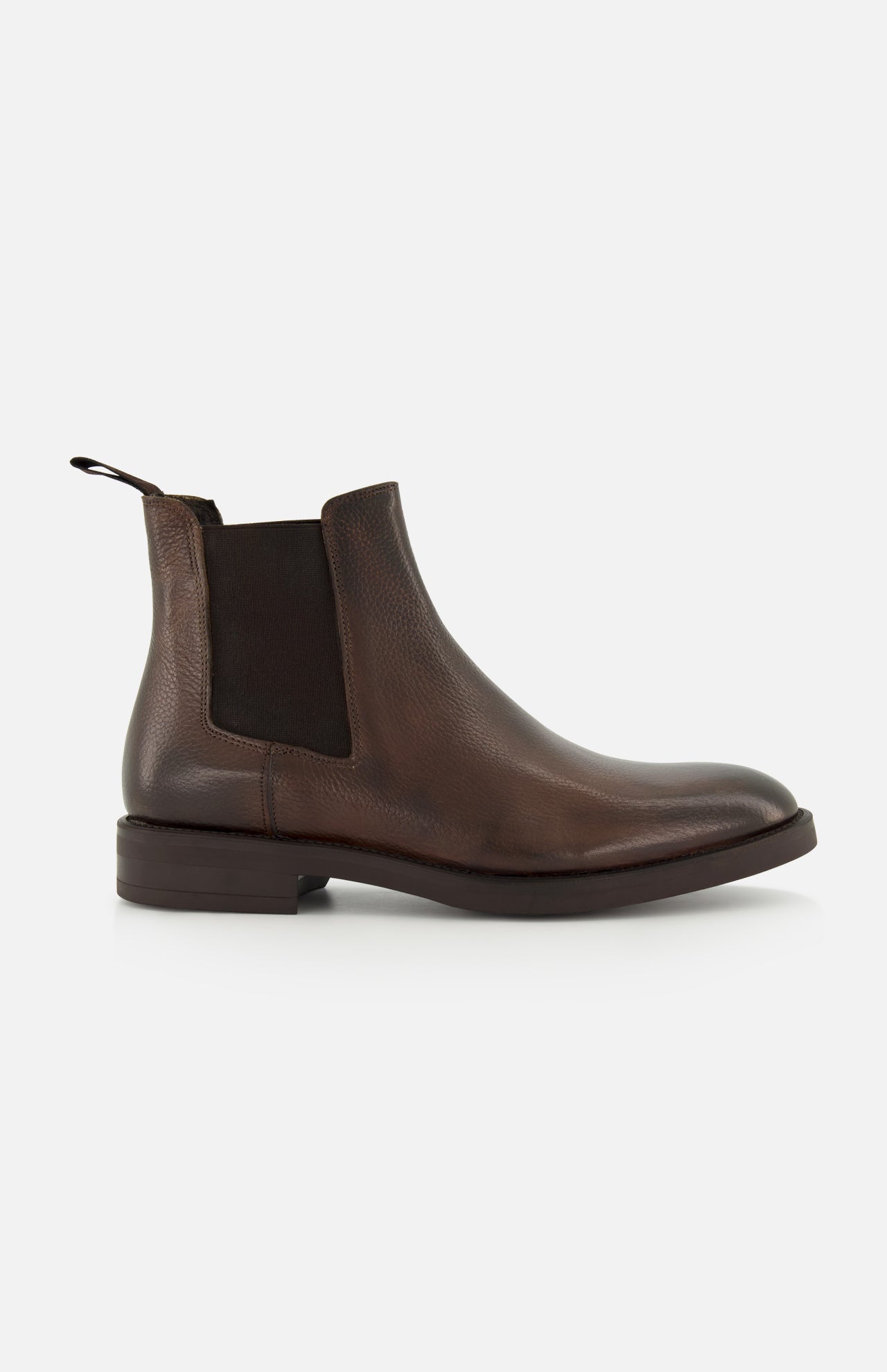 The Peabody Chelsea Boot by TO BOOT is a men’s brown grained leather boot with a black elastic side panel, back pull tab, and low heel, shown in profile on a white background.