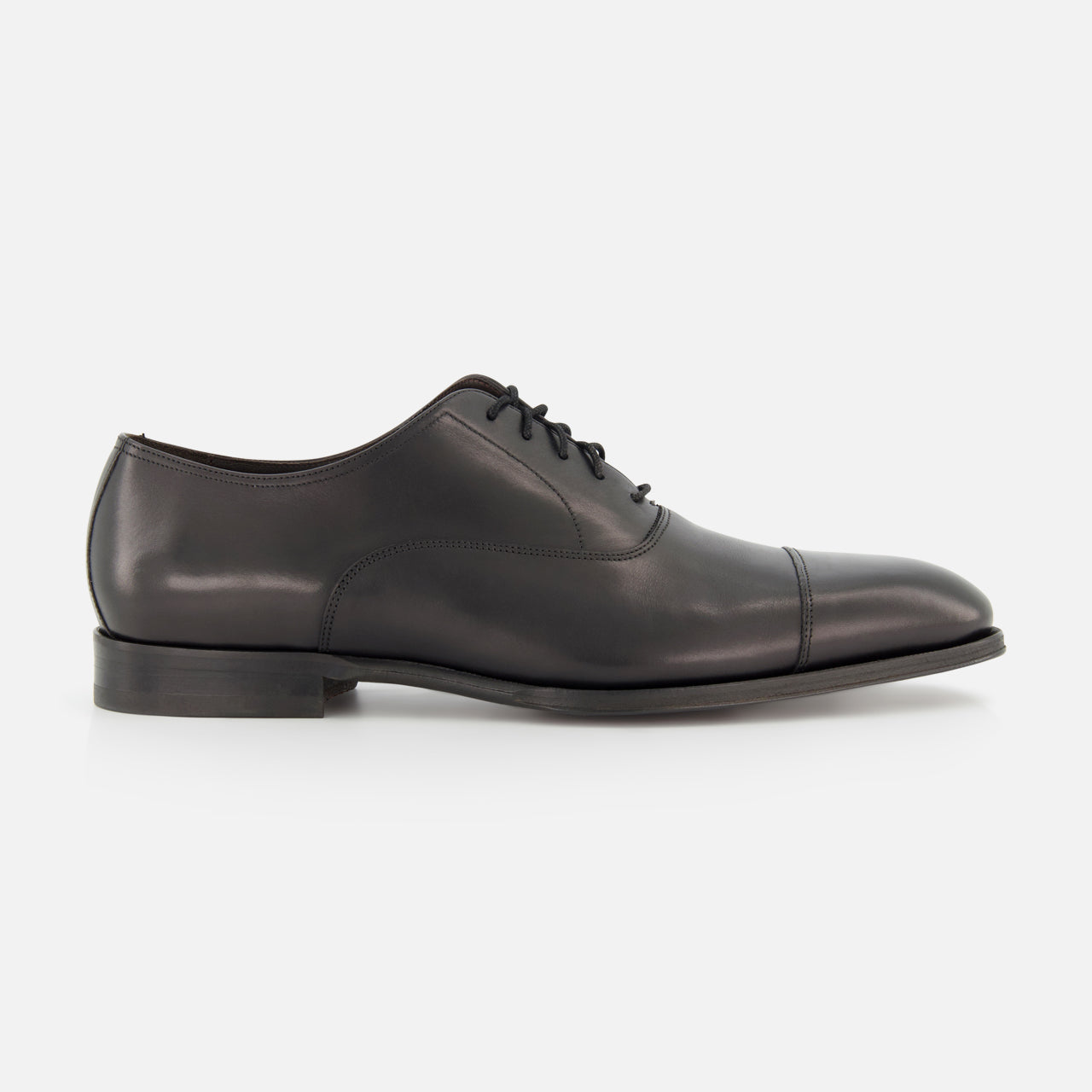 The TO BOOT Nico Leather Oxford is a hand-burnished black leather dress shoe with a cap toe, low heel, and black laces, shown in side profile against a white background—an elegant option inspired by classic Italian styles.