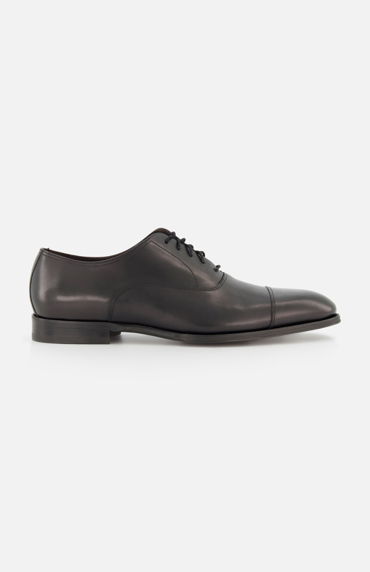 The TO BOOT Nico Leather Oxford is a hand-burnished black leather dress shoe with a cap toe, low heel, and black laces, shown in side profile against a white background—an elegant option inspired by classic Italian styles.