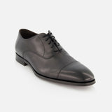 The TO BOOT Nico Leather Oxford is a black leather dress shoe with laces, low heel, and cap toe, hand burnished for a refined finish and shown on a white background.