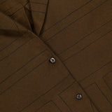 Close-up of TOTEME’s Monogram Flannel PJ Top in dark brown, featuring a geometric stitched pattern, four glossy buttons, and a small white label at the upper left—all highlighting its relaxed silhouette.