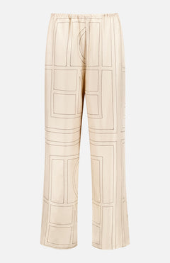 TOTEME’s Monogram Silk PJ Bottoms are ivory, straight-leg silk twill pants with a loose fit and elastic waistband, featuring a geometric monogram pattern in brown.