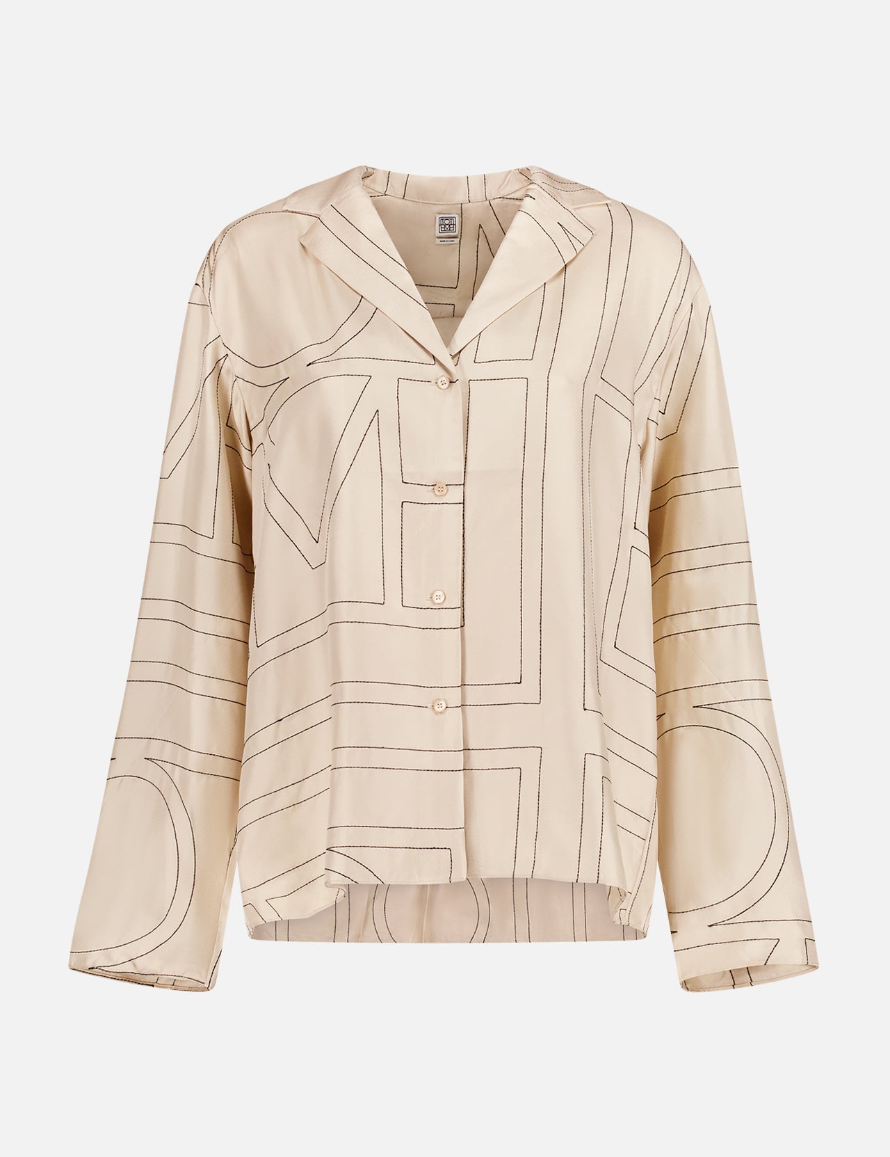The TOTEME Monogram Silk PJ Top is a beige long-sleeve, wide-collar shirt featuring a dark brown abstract monogram print and relaxed fit, offering an elegant update to the classic ivory blouse.