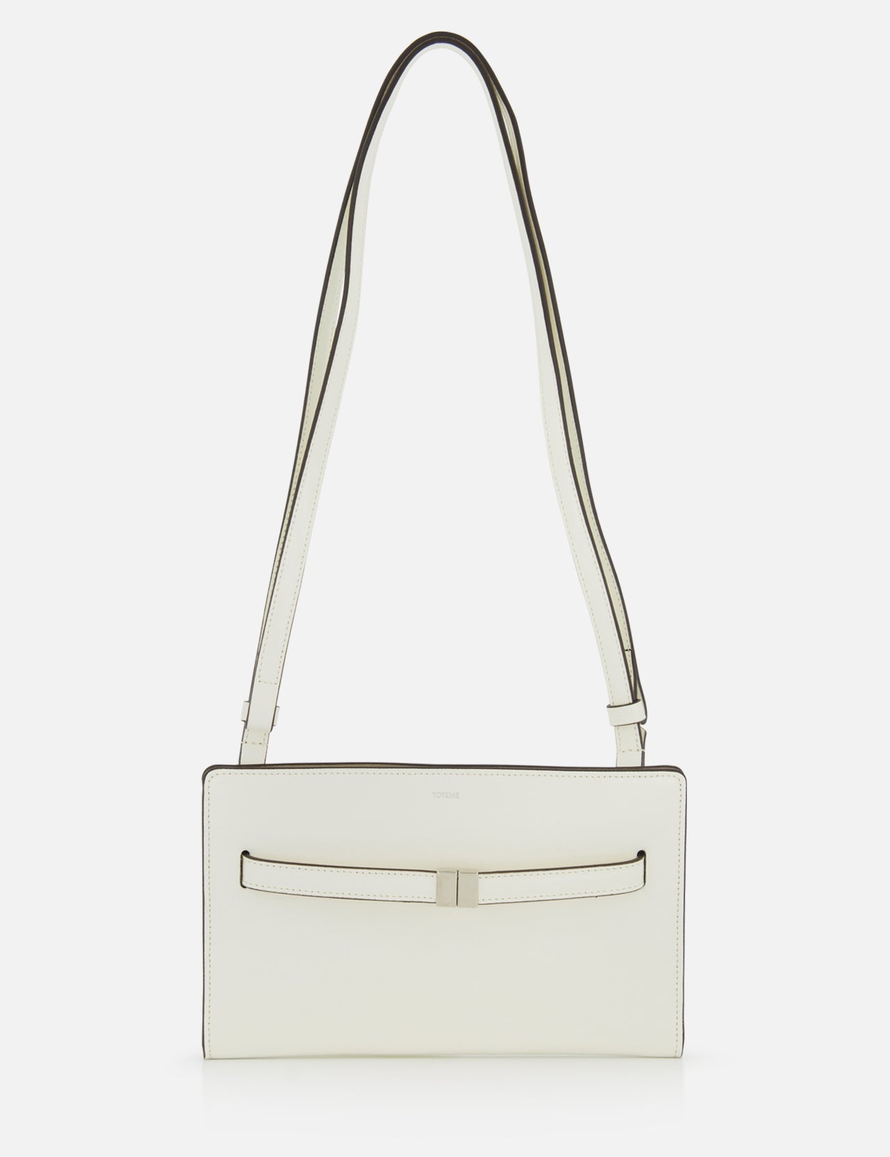 The TOTEME Belted Naplack Crossbody Bag is a minimalist white leather handbag with a long strap, subtle black trim, and a slim horizontal accent on the front. Made in Italy. Displayed against a plain white background.