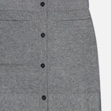 Here is a revised version of your sentence using the provided product data: A close-up of the TOTEME Buttoned Cashmere Skirt, a slim fit grey mini skirt featuring black buttons down the front, two horizontal seams, and subtle patch pockets, displayed on a plain white background.