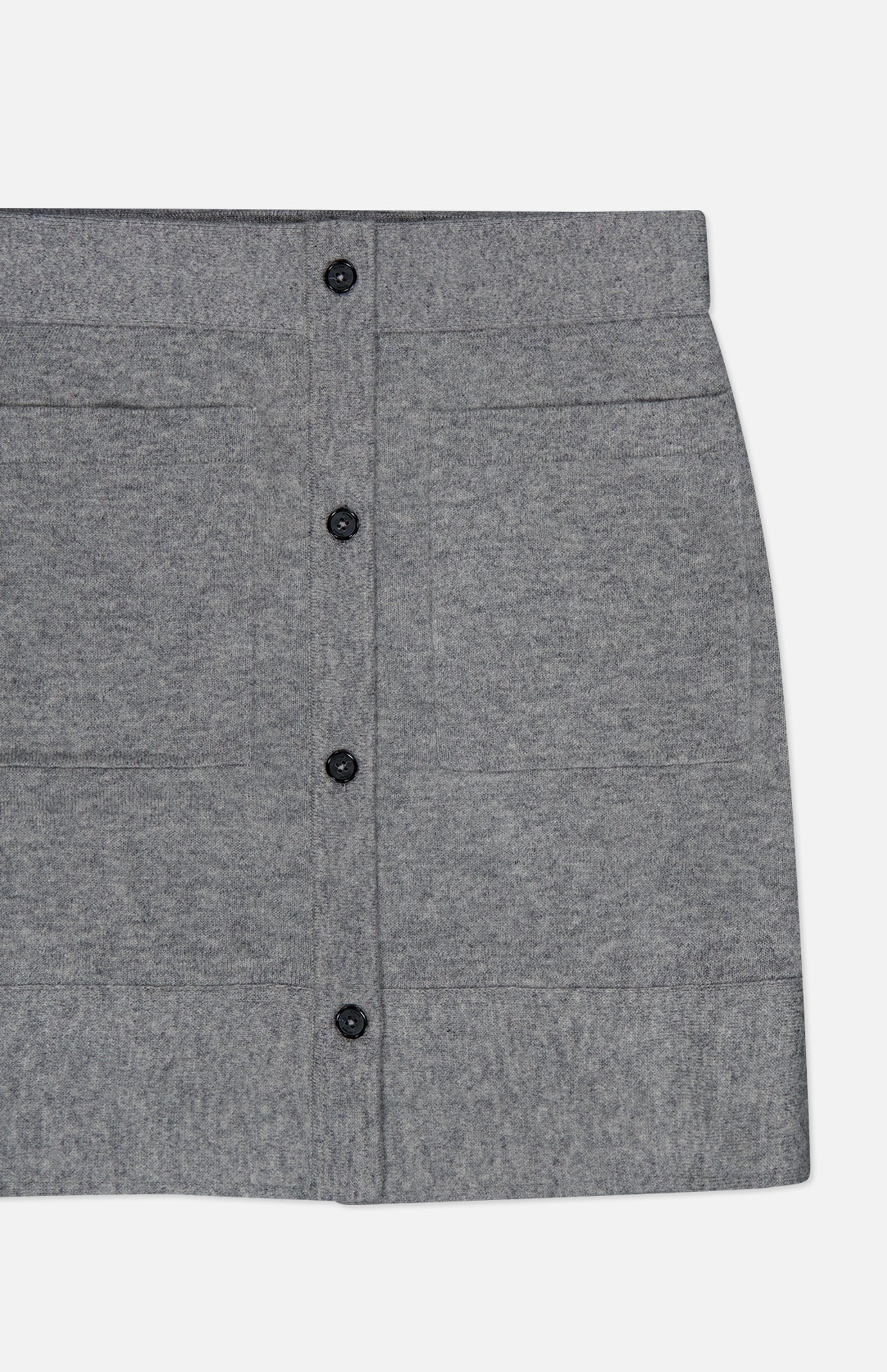 Here is a revised version of your sentence using the provided product data: A close-up of the TOTEME Buttoned Cashmere Skirt, a slim fit grey mini skirt featuring black buttons down the front, two horizontal seams, and subtle patch pockets, displayed on a plain white background.