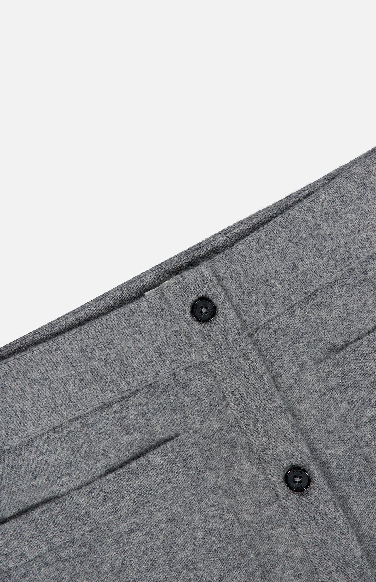 Detailed close-up of the TOTEME Buttoned Cashmere Skirt in grey, showcasing its slim-fit waistband with two black buttons, vertical seams, and subtle patch pockets for added detail.