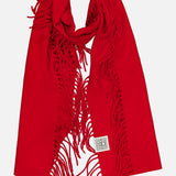 A vibrant TOTEME Wool and Cashmere Tassel Scarf in bright red, featuring fringed edges and a small white rectangular patch with a black geometric design, displayed on a white background. Expertly crafted in Italy, this luxurious scarf blends bold color with sophisticated style.