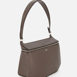 A TOTEME Clip Leather Shoulder Bag in dark brown leather, featuring a wide strap, silver zipper, and minimalist box bag design, is photographed against a plain white background.