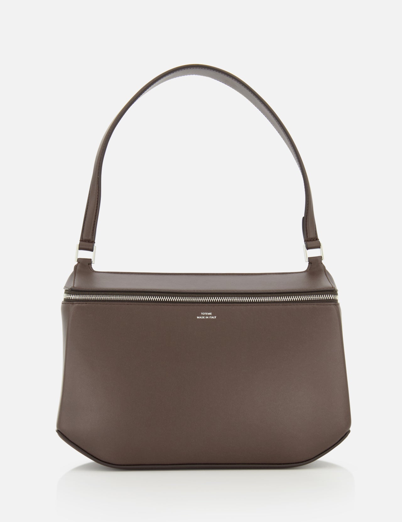 The TOTEME Clip Leather Shoulder Bag, crafted in Italy from dark brown leather, showcases a minimalist design with a wide strap and silver zipper, displayed against a plain white background.