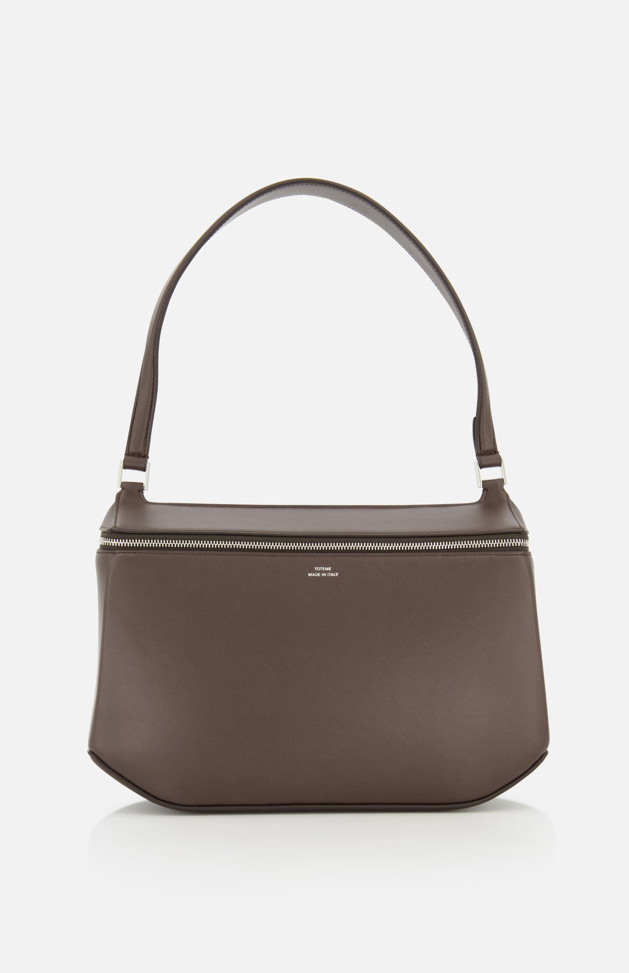 The TOTEME Clip Leather Shoulder Bag, crafted in Italy from dark brown leather, showcases a minimalist design with a wide strap and silver zipper, displayed against a plain white background.