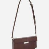The TOTEME Clip Lizard-Embossed Shoulder Bag is a brown leather box bag with an adjustable strap and a rectangular silver accent, expertly crafted in Italy, shown against a plain white background.