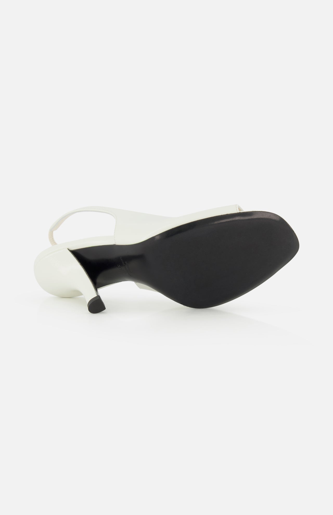The TOTEME Contour Naplack Slingback Heel, featuring white leather and a black sole, is shown on its side to highlight the heel and bottom against a plain white background.