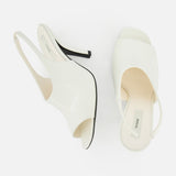 A pair of TOTEME Contour Naplack Slingback Heels in white leather, one on its side showing the black heel, the other upright revealing the insole and label. Both peep toe shoes are set against a plain white background.