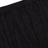 Close-up of the waistband and upper section of TOTEME's Crinkled Knit Pencil Skirt in black, made from lightweight fabric—ideal for achieving a sleek monochromatic look.
