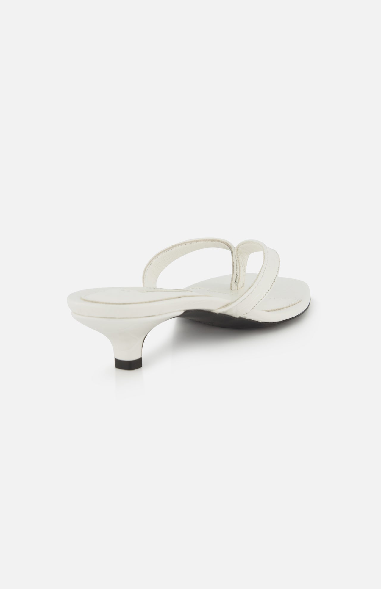 The Croco Embossed Heeled Flip Flops by TOTEME are white sandals in croco-embossed leather with a low kitten heel and two thin straps, shown from a rear angled view on a plain white background.