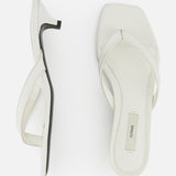 A pair of white Croco Embossed Heeled Flip Flops by TOTEME with square toes and crisscross straps in croco-embossed leather, shown from the side and top on a plain white background. One sandal displays the TOTEME label on the insole.