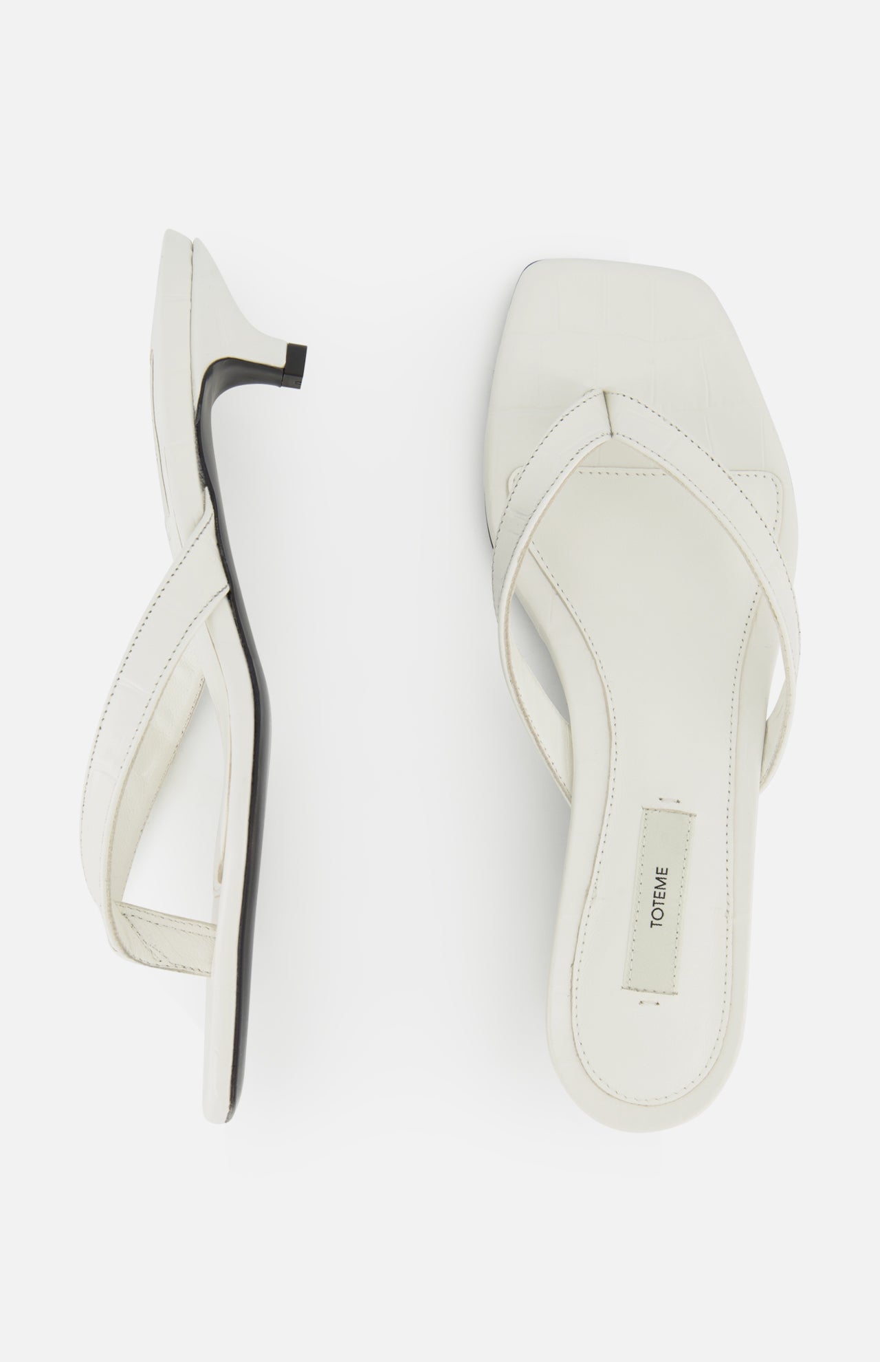 A pair of white Croco Embossed Heeled Flip Flops by TOTEME with square toes and crisscross straps in croco-embossed leather, shown from the side and top on a plain white background. One sandal displays the TOTEME label on the insole.