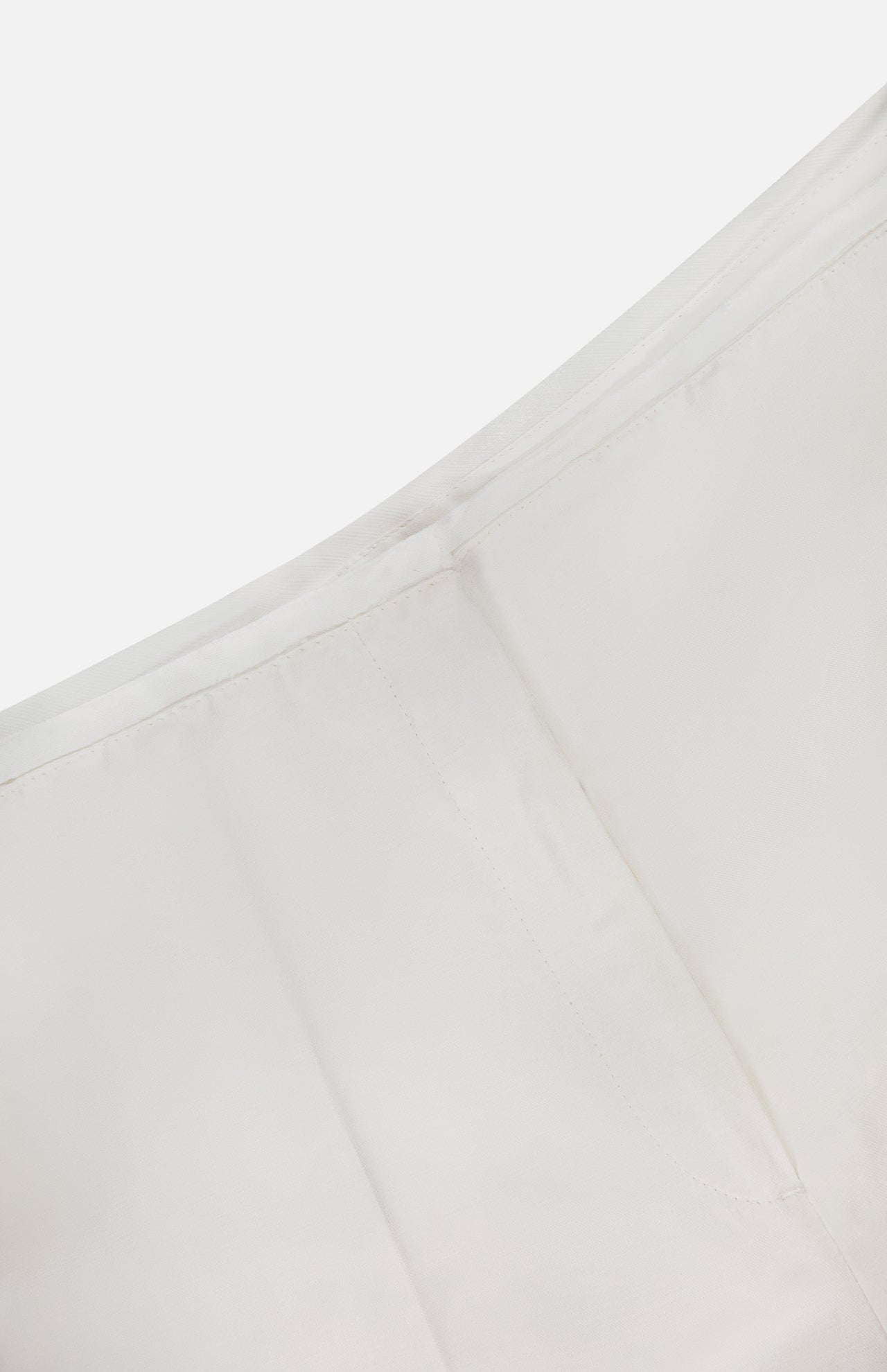 Close-up of white fabric with subtle stitching and seams from TOTEME's Easy Raw Edge Trouser Pants, shown against a plain white background.