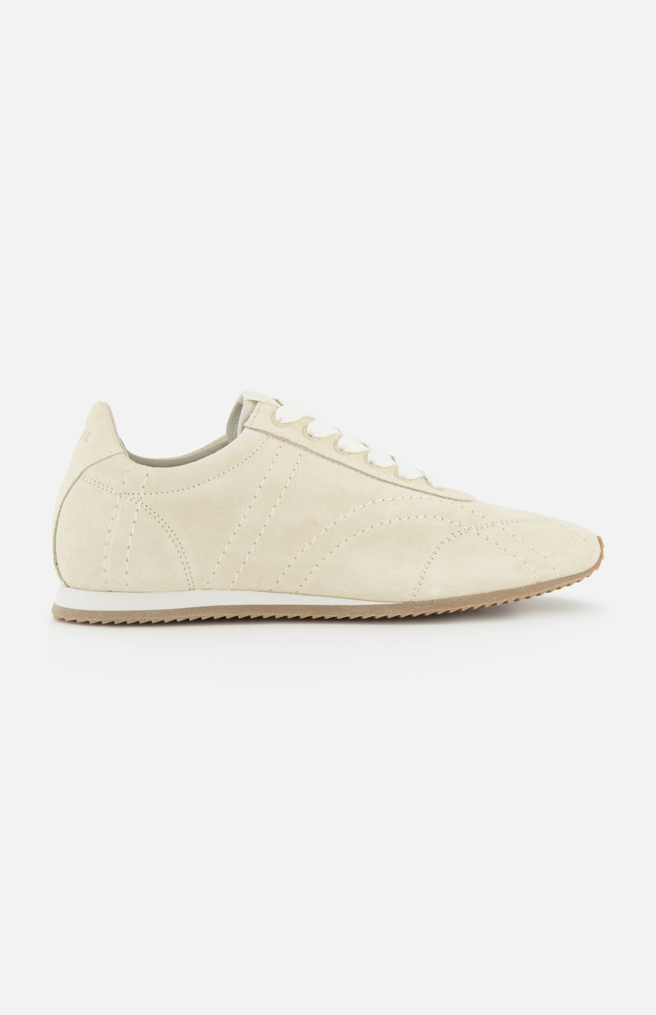 A side view of TOTEME's Flex Suede Low Profile Sneakers in beige, featuring white laces and a light brown rubber sole, photographed on a plain white background—expertly crafted in Italy for timeless appeal.