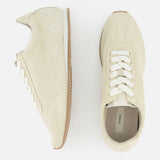TOTEME’s Flex Suede Low Profile Sneakers, expertly crafted in Italy, are shown on a white background with white laces and brown rubber soles—one displayed side-on, the other from above.
