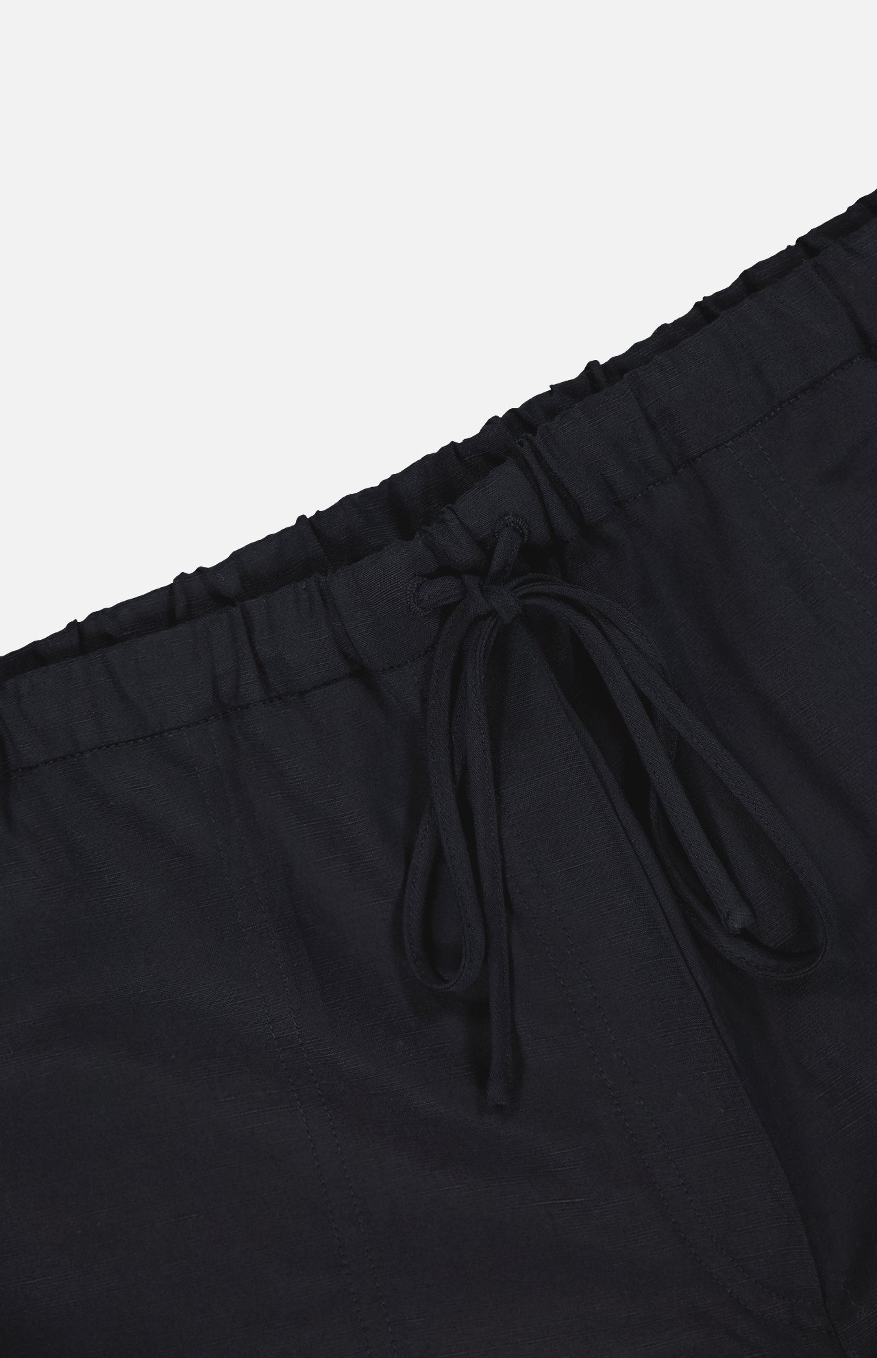 Close-up of TOTEME's Fluid Drawstring Trouser Pants in black, featuring a bow-tied drawstring waist and crafted from soft lyocell linen, shown against a plain white background.