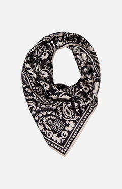 The TOTEME Hankie Silk Paisley Scarf, featuring an intricate black and white floral and paisley print, is folded into a triangle against a plain white background.