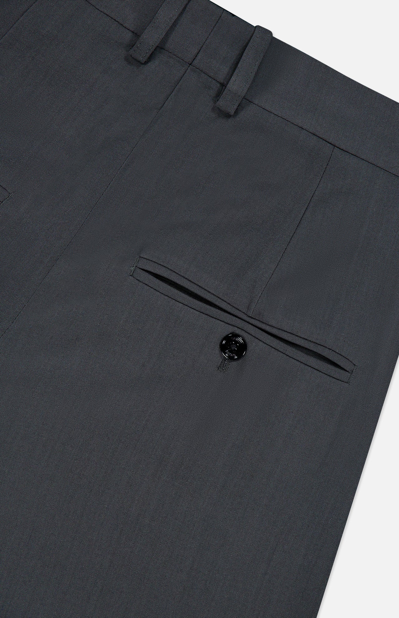 Close-up of the back pocket on TOTEME’s High-Waisted Trouser Pants in dark grey, showcasing a single black button and belt loops at the waistband. These office pants feature a sleek, high-rise fit for a polished appearance.