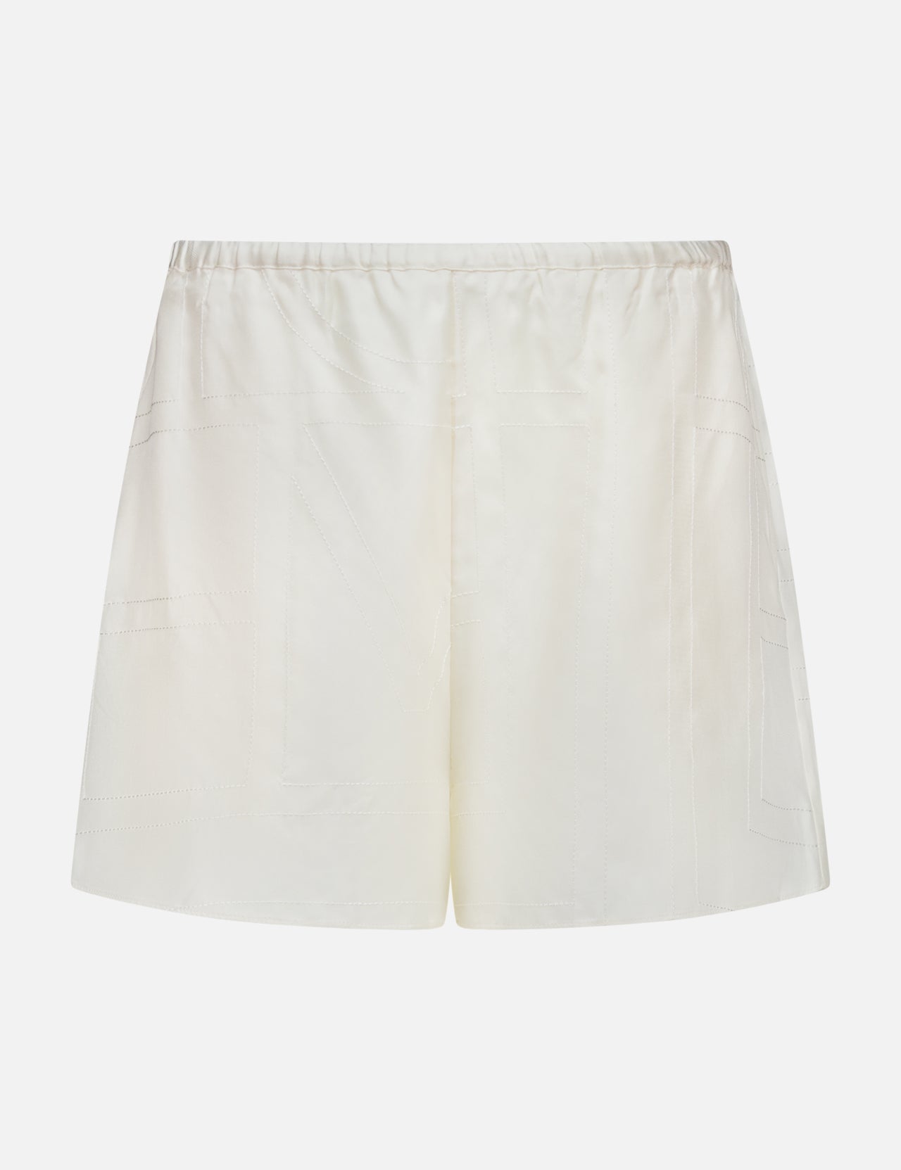 TOTEME Monogram Silk PJ Shorts feature cream satin fabric, an elastic waistband, and subtle stitched detailing. Photographed against a plain white background, these shorts evoke classic silk sleepwear styles.