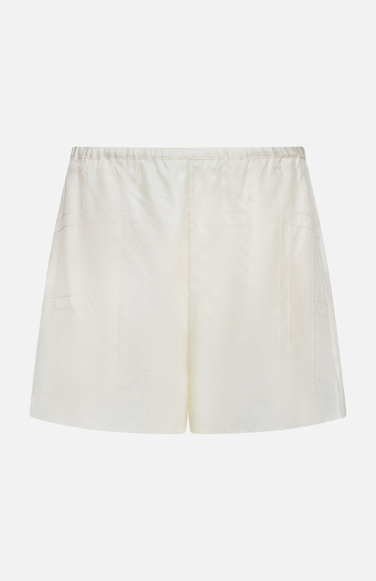 TOTEME Monogram Silk PJ Shorts feature cream satin fabric, an elastic waistband, and subtle stitched detailing. Photographed against a plain white background, these shorts evoke classic silk sleepwear styles.