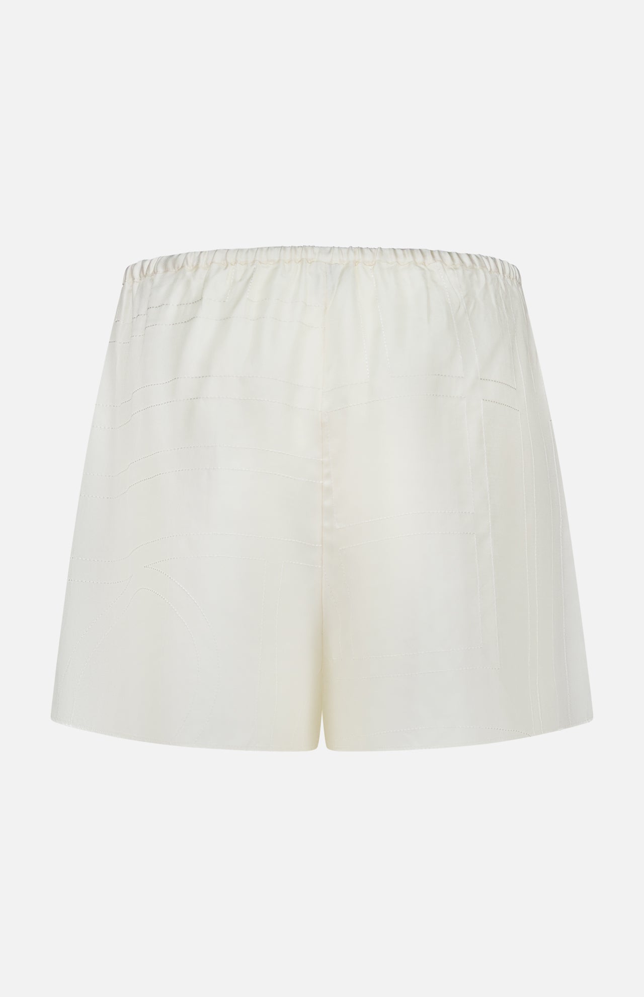 TOTEME Monogram Silk PJ Shorts shown against a white background. These cream silk shorts feature an elastic waistband, loose relaxed fit, minimal detailing, and an elegant embroidered monogram.