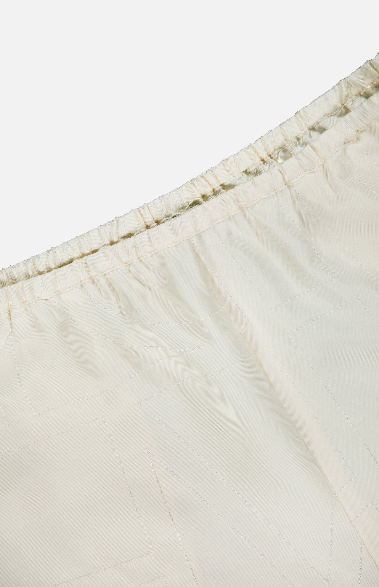 Close-up of TOTEME's Monogram Silk PJ Shorts, featuring an elastic waistband, subtle stitched patterns, and an embroidered monogram for a refined finish.