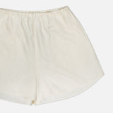 The TOTEME Monogram Silk PJ Shorts are off-white with an elastic waistband and embroidered monogram, shown against a plain white background.