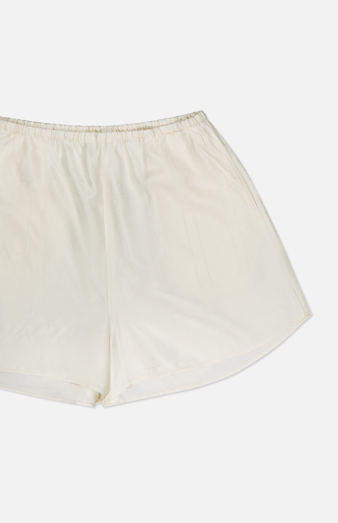 The TOTEME Monogram Silk PJ Shorts are off-white with an elastic waistband and embroidered monogram, shown against a plain white background.