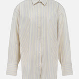 The TOTEME Oversized Pastel Striped Shirt is a long-sleeved, button-up shirt with a collar and wide cuffs, featuring vertical beige and white stripes. Shown against a plain white background.