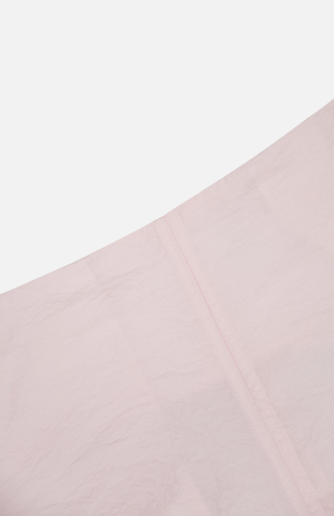 Close-up of TOTEME’s Silk-blend Parachute Skirt in pale pink, featuring lightly wrinkled fabric and a vertical seam, photographed against a white background.