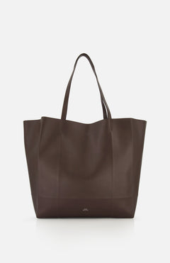 The TOTEME Roam Oversized Leather Tote Bag is shown against a white background. This large, dark brown bag has two handles and a minimalist design with no visible embellishments.