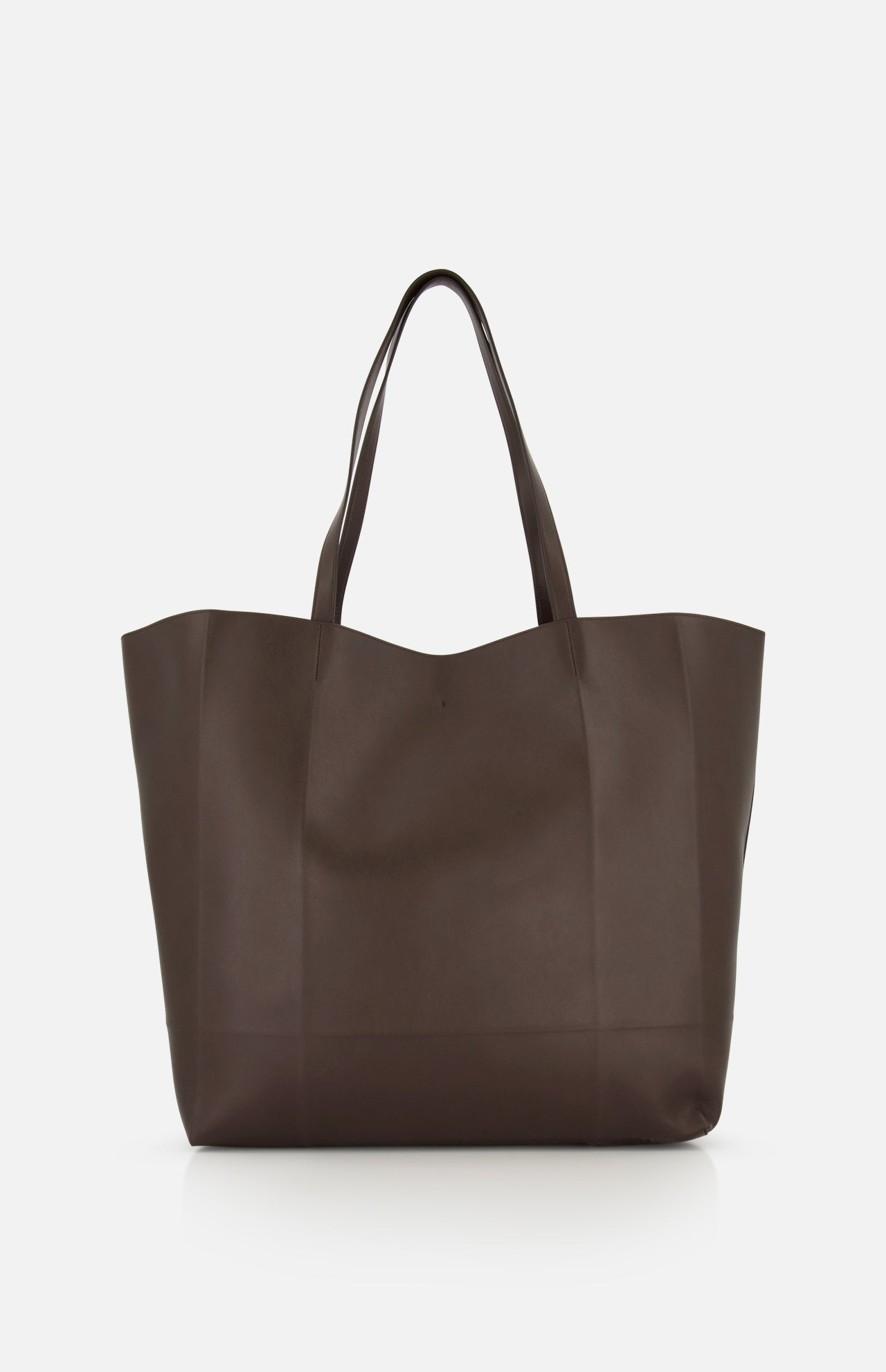 The TOTEME Roam Oversized Leather Tote Bag, made in Italy, features a minimalist dark brown design with two handles and an oversized silhouette, displayed against a plain white background.