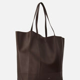 The TOTEME Roam Oversized Leather Tote Bag is a large, dark brown tote with two handles and a minimalist, slightly structured shape, displayed against a plain white background.