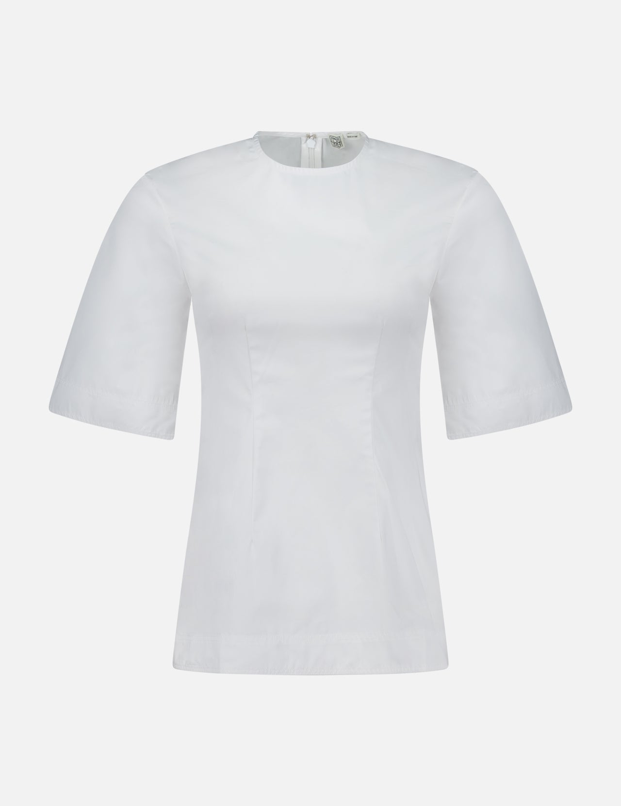 The TOTEME Sculptural Cotton Top is a designer women’s blouse in plain white with short sleeves, a round neckline, and a back zipper. Showcasing clean lines and timeless appeal, it is displayed against a white background.