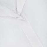 Close-up of TOTEME’s Sharp Poplin Dress Shirt in crisp white cotton, featuring a visible collar, MADE IN ITALY tag, and a concealed button-down front for subtle elegance.