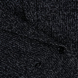 Close-up of the TOTEME Shawl-Lapel Cardigan’s black and white textured wool-blend fabric, featuring a subtle woven pattern, two black buttons along the front closure, and a small white TOTEME label in the top left corner.