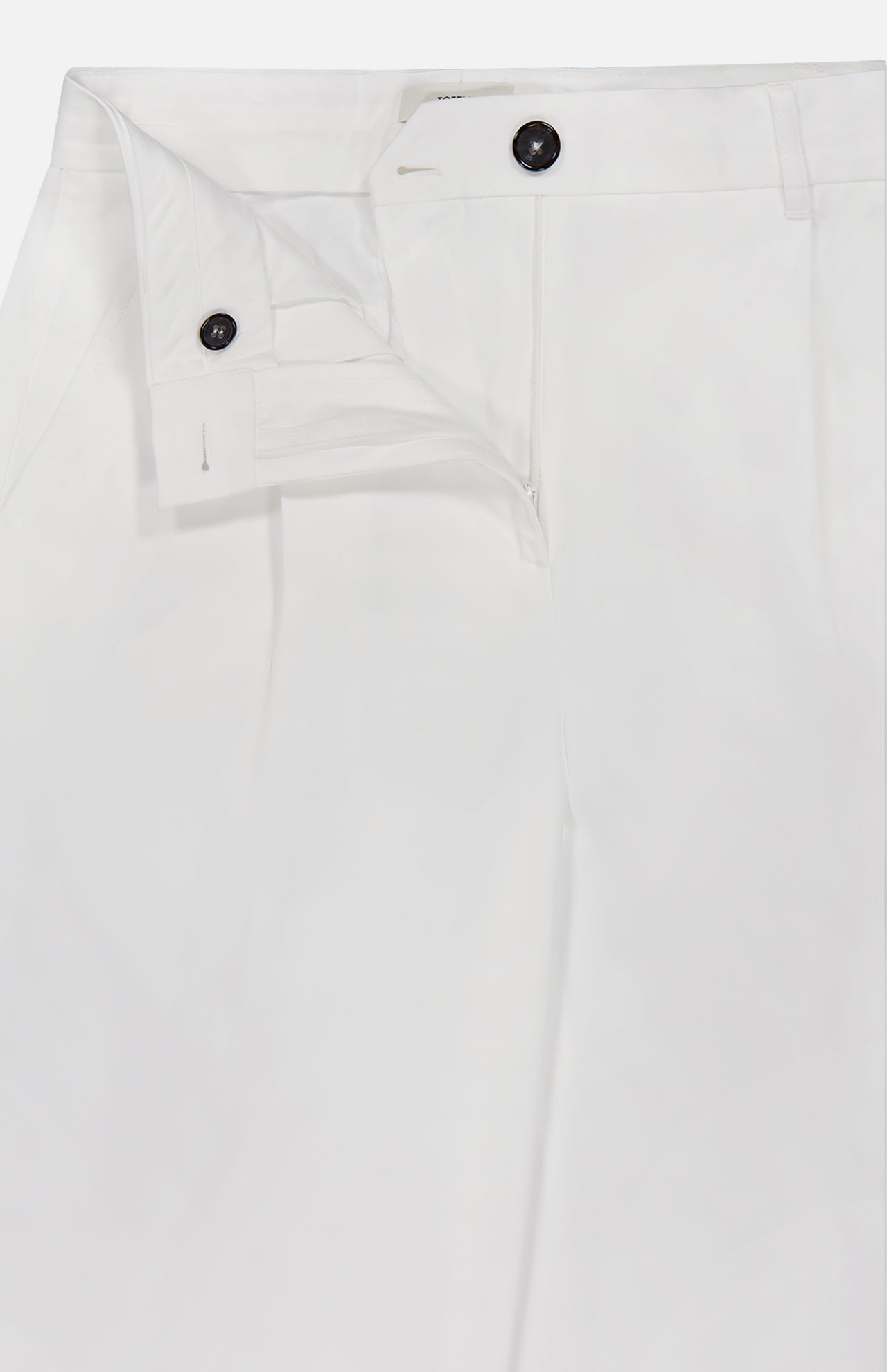 The TOTEME Single Pleat Cotton Trouser Pants feature a crisp, smooth cotton fabric and a white tailored silhouette. The partially open waistband reveals a black button and part of the zipper area, emphasizing their refined, modern design.