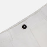 Close-up of the waistband and upper section of TOTEME’s Single Pleat Cotton Trouser Pants in white, showcasing a prominent dark button and belt loops against a plain background.