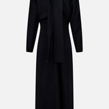 The TOTEME Slouch Waist Scarf Dress is a long-sleeve black midi dress featuring voluminous sleeves, a keyhole neckline with a wide matching necktie detail, and a fitted waist with a straight skirt, shown against a plain white background.