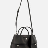 Introducing the TOTEME Small Mercer Leather Tote Bag in black, crafted from premium leather and adorned with silver studs. This designer tote features distinctive geometric flap accents on the sides, dual handles, and an adjustable shoulder strap. Expertly made in Italy, it is showcased against a plain white background.