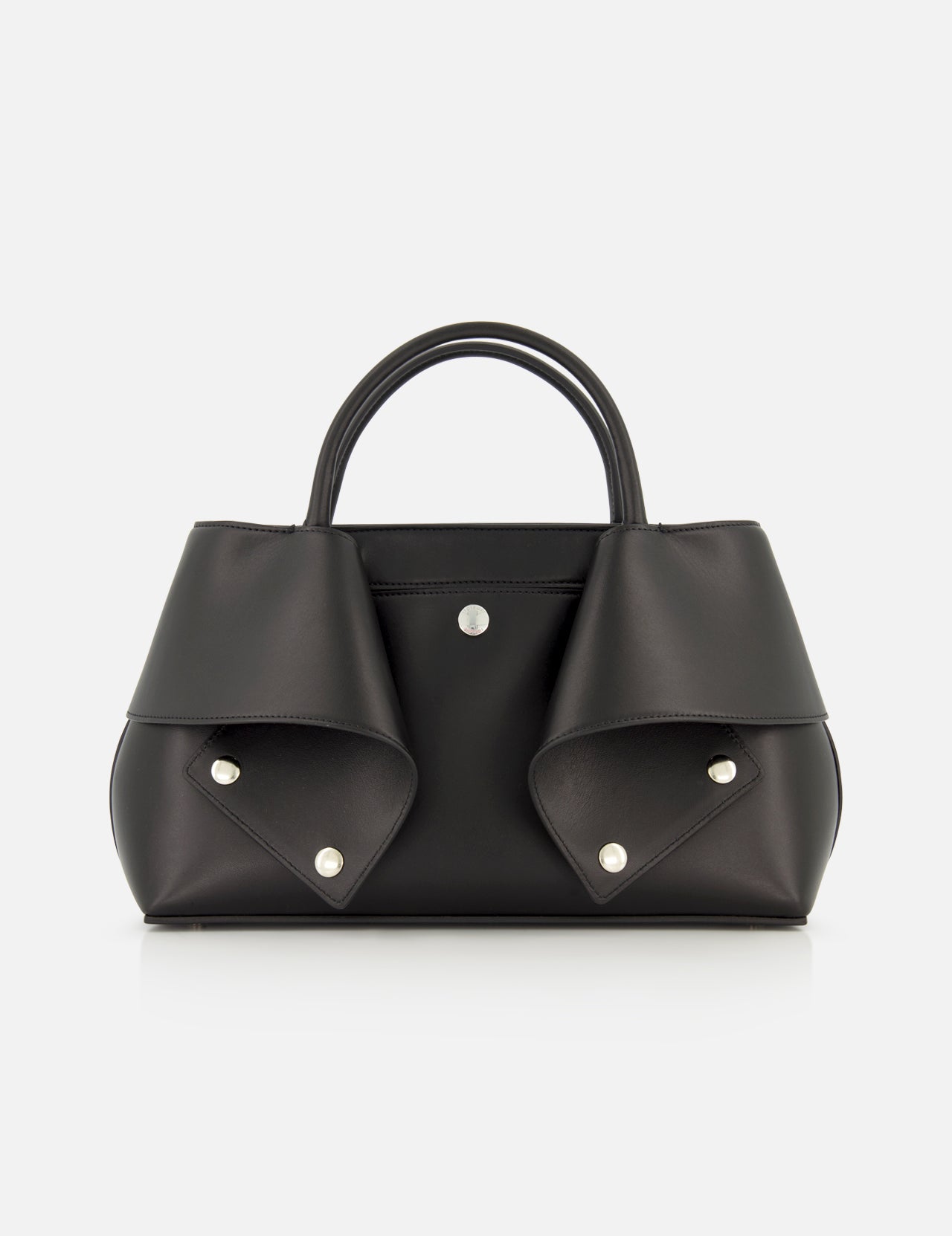 The TOTEME Small Mercer Leather Tote Bag features black leather with two short handles, silver button details, and folded flap accents on each side. Expertly crafted in Italy, this sophisticated designer tote is displayed against a plain white background.
