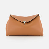 The TOTEME T-Lock Grained-Leather Clutch is an Italian-made tan leather bag featuring a flap closure, white stitching, and a central silver clasp, shown against a plain white background.