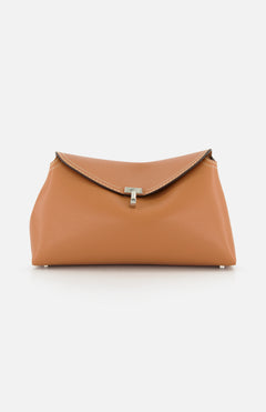 The TOTEME T-Lock Grained-Leather Clutch is an Italian-made tan leather bag featuring a flap closure, white stitching, and a central silver clasp, shown against a plain white background.