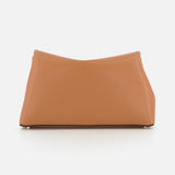 The TOTEME T-Lock Grained-Leather Clutch is a medium-sized, sculptural tan leather bag with a softly curved rectangular shape and visible top-corner stitching, shown on a plain white background.